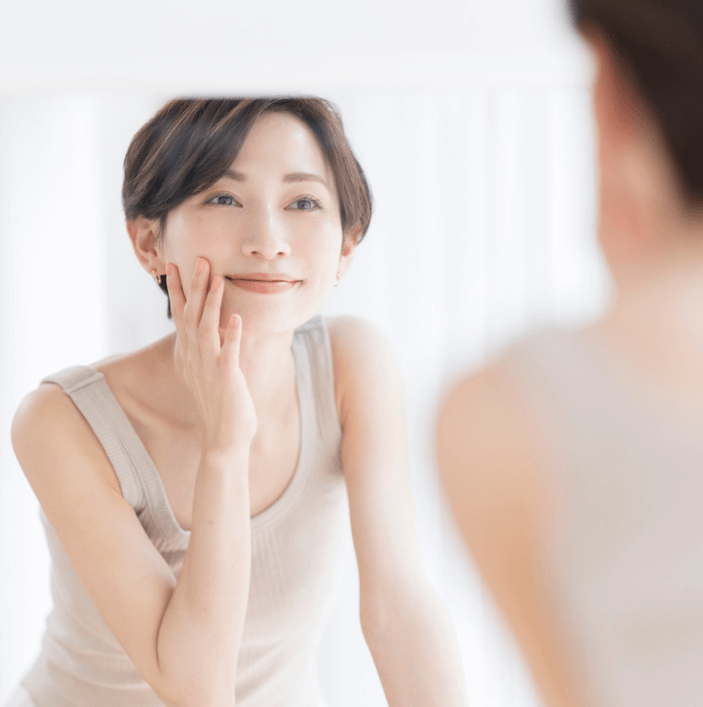 Woman applying Ultra Renew Body Oil for a refreshed and smooth skincare routine in front of a mirror.