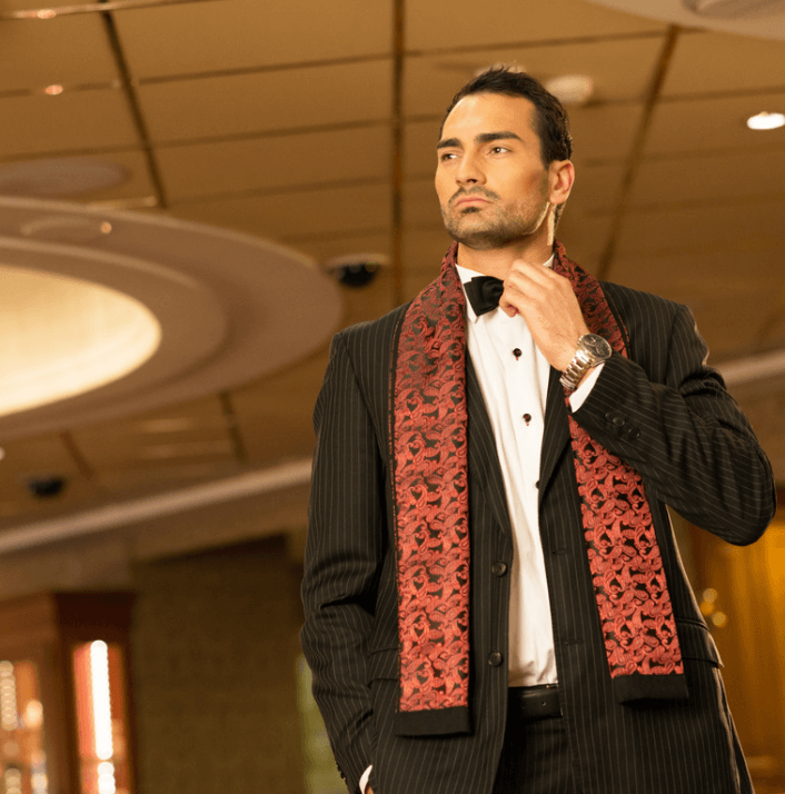 Model in a stylish tuxedo with a red patterned scarf showcasing a sophisticated look at an upscale event.