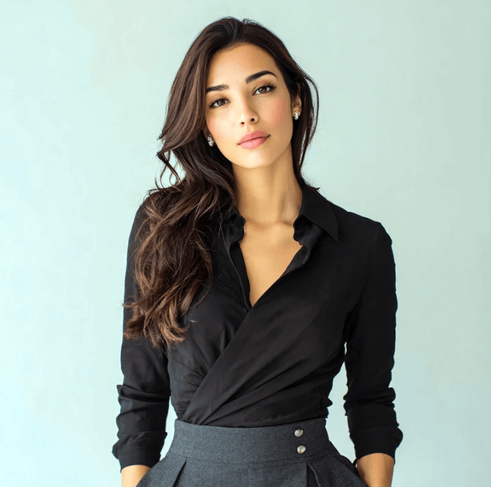Woman with long hair wearing a black blouse and gray skirt against a soft blue background.